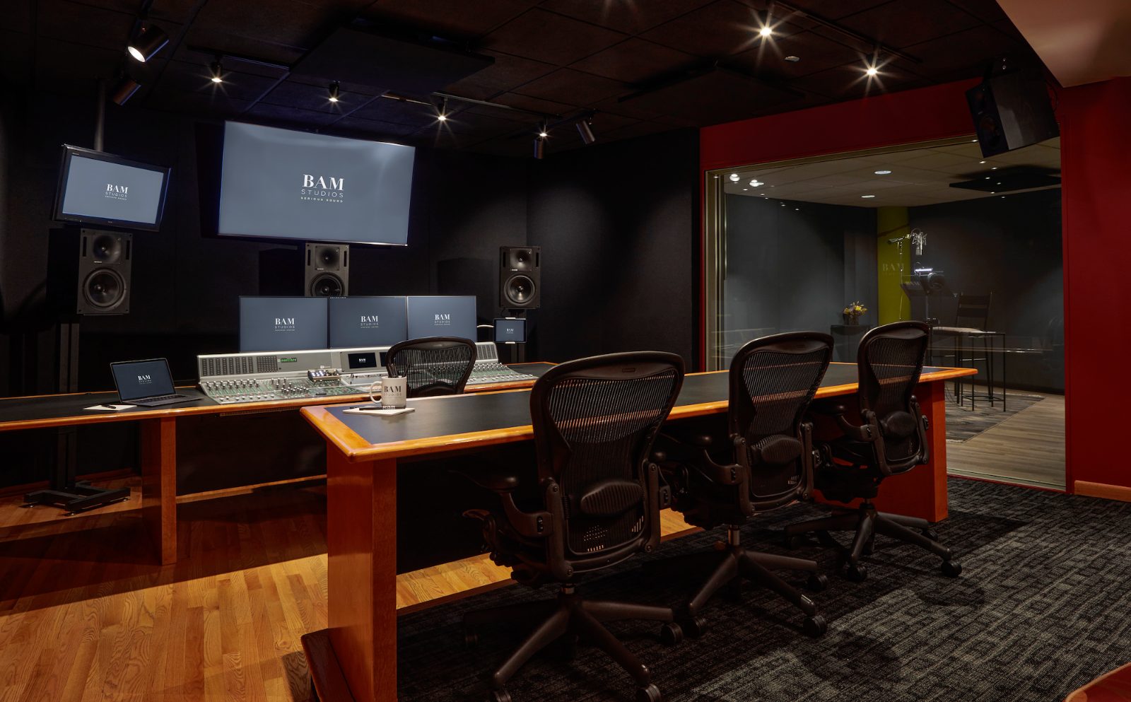Studio A control room — console, monitoring, and the booth beyond the glass