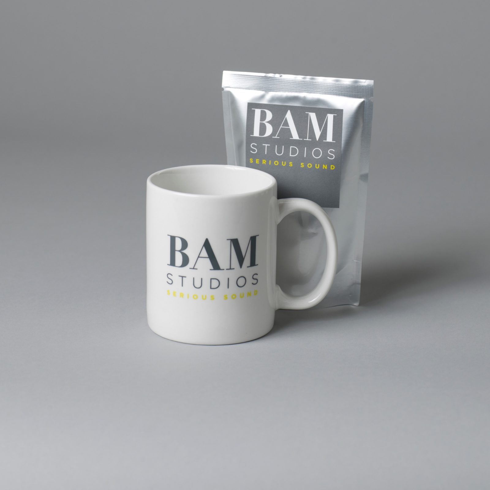 A branded BAM Studios mug and coffee sachet