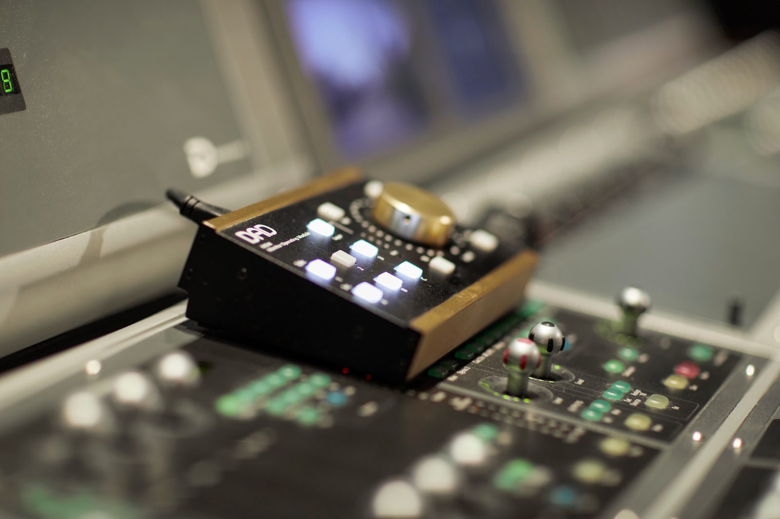 A DAD monitor controller on the desk beside a mixing console
