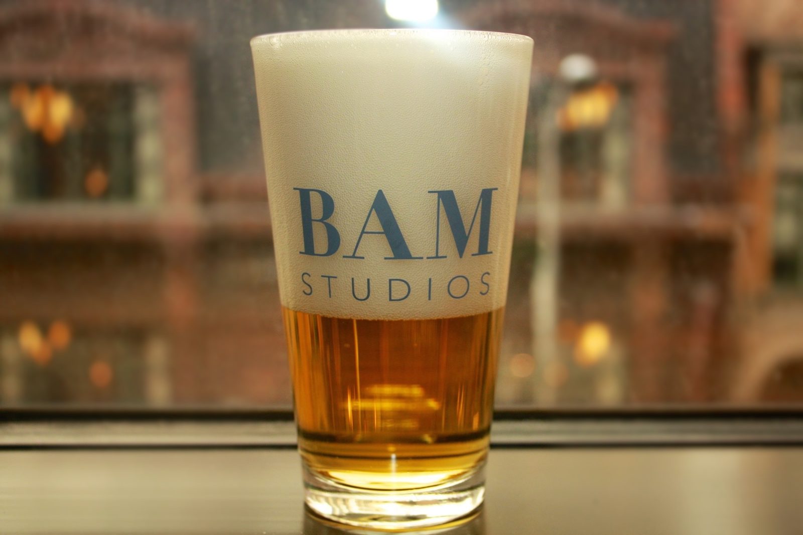 A branded BAM Studios pint glass on the window ledge